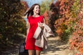 Female person in red dress walking under autumn trees