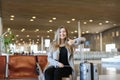 Female person sitting in airport hall with modern tablet near valise and showing thumbs up. Royalty Free Stock Photo