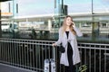 Female person standing with valise and talking by smartpone near airport. Royalty Free Stock Photo