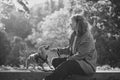 Female pet instructor in autumn clothes playing dachshund puppy in autumn park