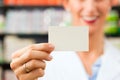 Female pharmacist with business card in pharmacy