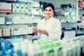 Female pharmacist checking assortment of drugs in pharmacy