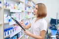 Female pharmacist with folder examinating medicaments.