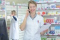 female pharmacist on phone call reaching medication Royalty Free Stock Photo