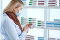 female pharmacist in a protective mask standing near a pharmacy display case . Royalty Free Stock Photo