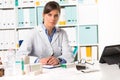 Female pharmacist sat at desk writing notes Royalty Free Stock Photo