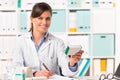 Female pharmacist sat at desk writing notes Royalty Free Stock Photo