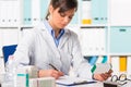 Female pharmacist sat at desk writing notes Royalty Free Stock Photo