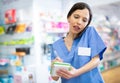 Female pharmacist talking on mobile phone and taking notes in a notebook in pharmacy Royalty Free Stock Photo