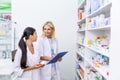 female pharmacists with medication and clipboard working together