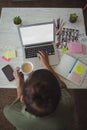 Female photo editor holding coffee cup while using laptop in office