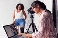 Female Photographer In Digital Studio Shooting Images On Camera Tethered To Laptop Computer