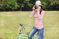 Female photographer holding camera and sitting bike