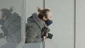 Female photographer looks out of window with camera. Action. Masked paparazzi woman with camera looks out of window Royalty Free Stock Photo