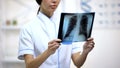 Female physician attentively looking at lungs x-ray, risk of bronchitis, health