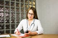 Female physician medicine doctor or pharmacist sitting at work table, holding jar or bottle of pills in hand and writing Royalty Free Stock Photo