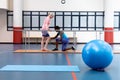 Female physiotherapist assisting disabled senior woman walk with parallel bars in sports center Royalty Free Stock Photo