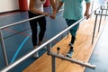 Female physiotherapist helping disabled senior woman walk with parallel bars in sports center Royalty Free Stock Photo