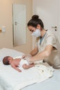 Female physiotherapist performing a visceral-digestive assessment on a newborn baby.