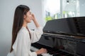 Female pianist in dress casual style sitting at classic grand piano in the school and looking forward. Professional musician young Royalty Free Stock Photo