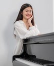 Female pianist in dress casual style standing at classic grand piano in the school and looking camera. Professional musician young Royalty Free Stock Photo