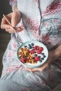 Female in pijama eating yogurt with granola and berries Royalty Free Stock Photo