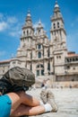 Female Pilgrim Backpacker`s legs and bag close up image. She sitting on the Obradeiro square plaza in Santiago de Compostela,