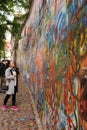 Female with pink sneakers watches graffiti on John Lennon Wall in Prague, Czech Republic