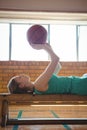 Female player playing with basketball while lying on bench in court Royalty Free Stock Photo