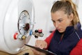 Female plumber by boiler researching information on tablet Royalty Free Stock Photo