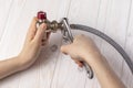 Female plumber connecting flexible hose to stopcock using a wrench. Royalty Free Stock Photo