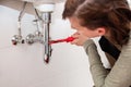 female plumber repairs or installs pipes under a sink