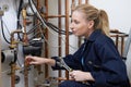 Female Plumber Working On Central Heating Boiler