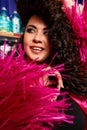 Female Plus size model posing in the studio, front face portrait, in rose feathers. The woman is looking with sensuality