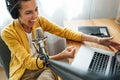 Female podcaster recording broadcasting into microphone using laptop