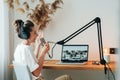 Female podcaster recording broadcasting into microphone using laptop