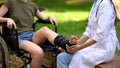 Female podiatric physician examining injured patient leg, ankle supporting brace