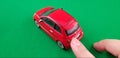 Female pointing finger touches back of red small Fiat 500 car