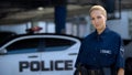 Female police officer smiling, standing near patrol car, maintenance of order Royalty Free Stock Photo