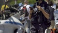 Female police officer standing next to motorbike, checking mobile phone on duty