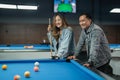 female pool player smiling while standing holding the cue stick beside the pool Royalty Free Stock Photo