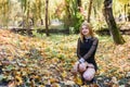 Female porteait in autumn park. Beaurtiful woman in black dress posing with yellow trees