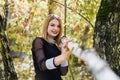 Female porteait in autumn park. Beaurtiful woman in black dress posing with yellow trees