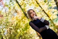 Female porteait in autumn park. Beaurtiful woman in black dress posing with yellow trees