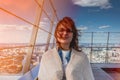 Female portrait on the background of the city. Young woman on the roof of a skyscraper. Girl on the background of the city below.