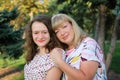 Female portrait of a beautiful plus size blond, blue-eyed mother and daughter in the park during summer. Family day Royalty Free Stock Photo