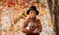Female portrait. beautiful young blonde girl in a brown warm sweater, black felt hat hugs a small pumpkin. rowan berries in the Royalty Free Stock Photo