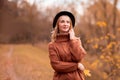 Female portrait. beautiful young blonde girl in a brown warm sweater, black felt hat smiling. In the background are yellow autumn Royalty Free Stock Photo