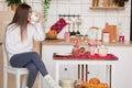 Female portrait. beautiful young girl with blond long hair in a white sweater sits and drinks coffee in the kitchen decorated for