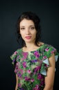 Female portrait of cute young girl in green dress with pink flowers posing in studio on black background Royalty Free Stock Photo